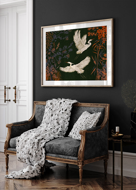 a black and white sofa with a white throw blanket and two white pillows, set against a dark wall with a framed painting of two white birds in flight above it.