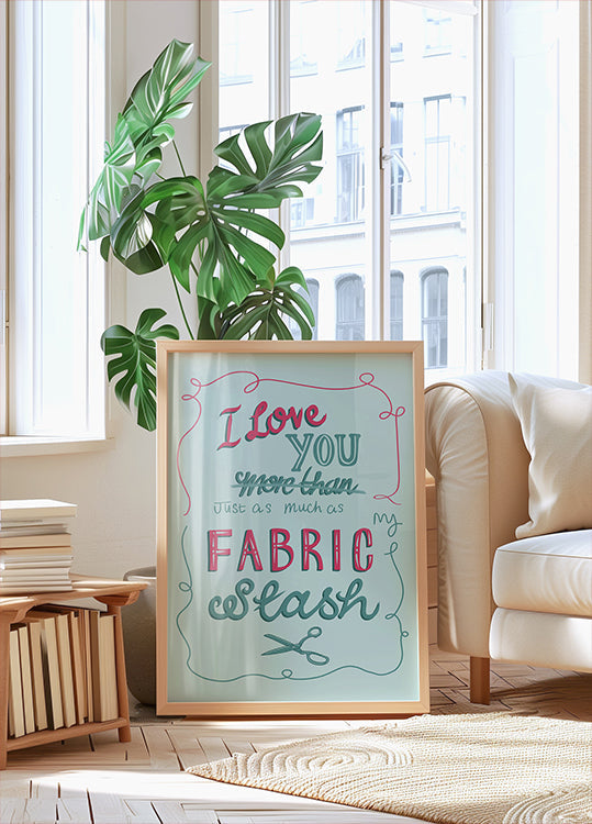 A framed poster with a handwritten message is displayed in a living room, with a potted plant and a bookshelf visible in the background.